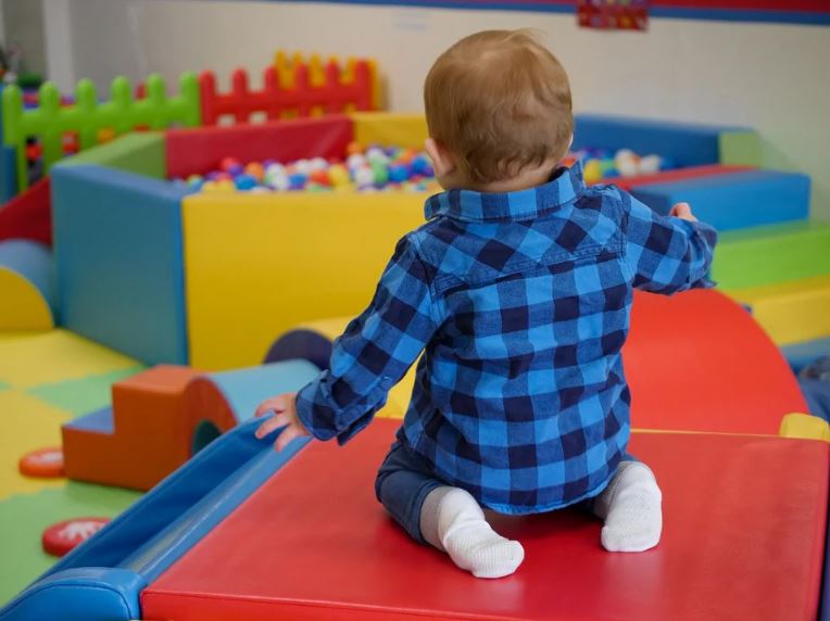 toddler kneeling in a colourful play area