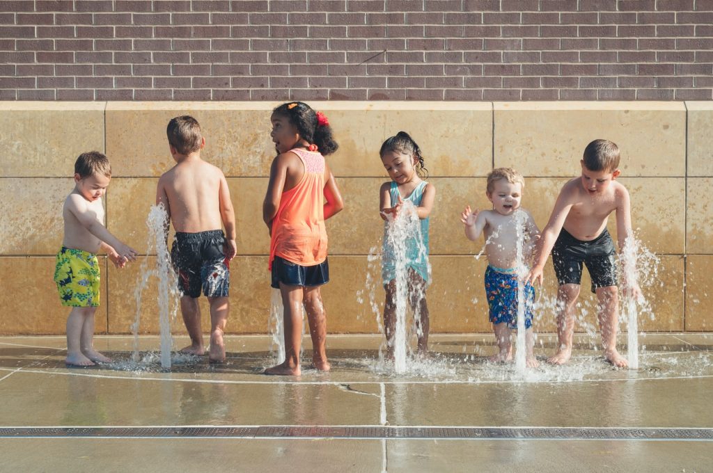 a group of children playing with water fountains
